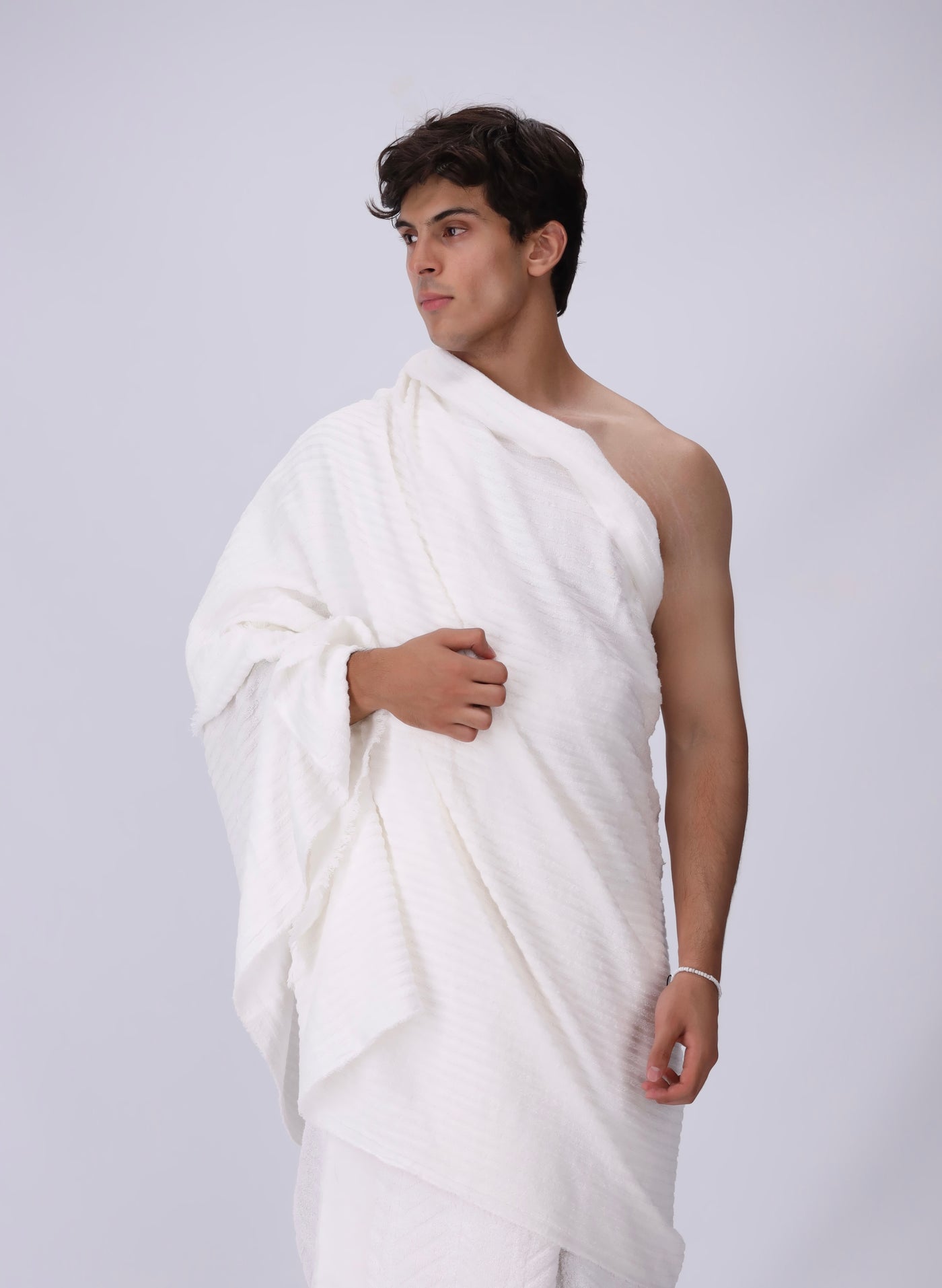 Man wearing a white draped garment against a plain background