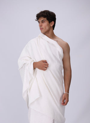 Man wearing a white draped garment against a plain background